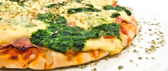 Close-up of a spinach and cheese pizza slice.