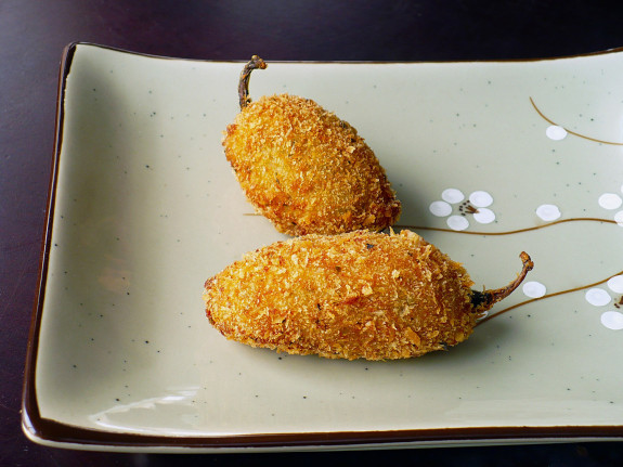 Two crispy fried stuffed jalapeños on a plate.