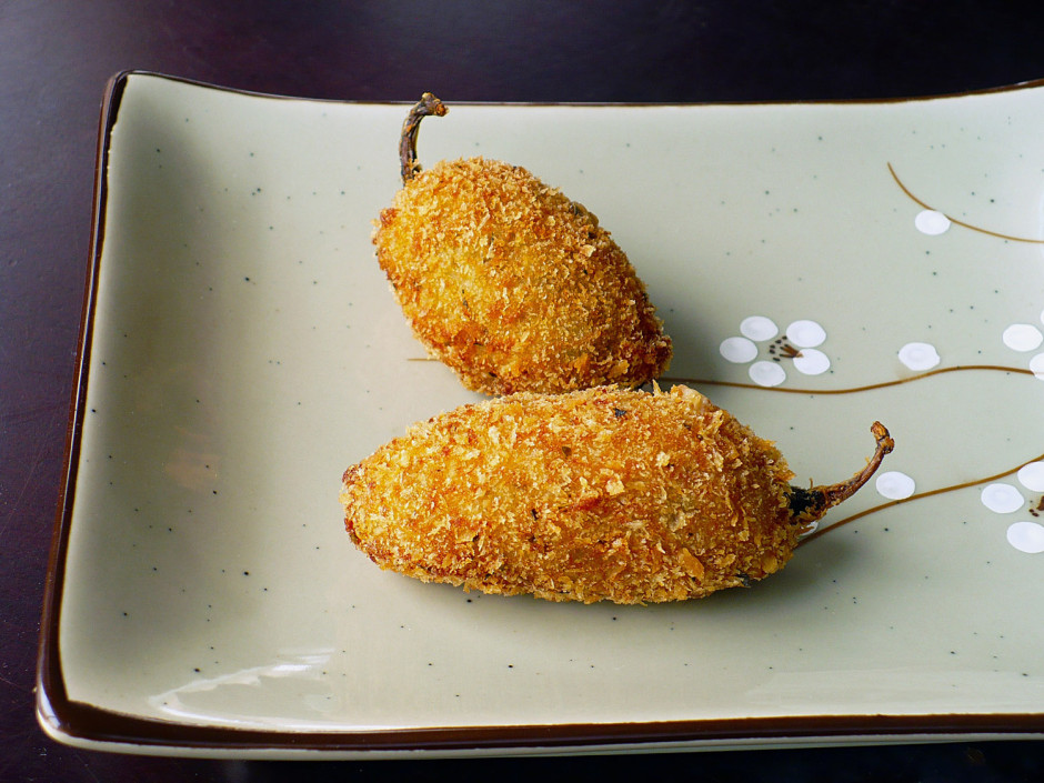 Two crispy fried stuffed jalapeños on a plate.