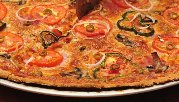 A vegetable pizza topped with tomatoes, onions, olives, and peppers.