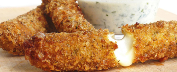 Close-up of crispy breaded chicken strips with a creamy dip.