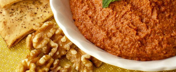 Close-up of walnut pesto sauce in a bowl with walnuts beside it.
