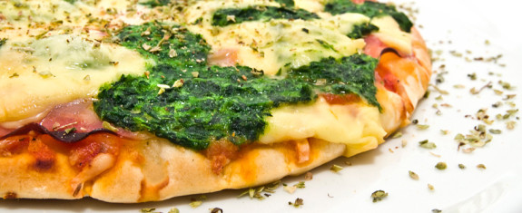 Close-up of a spinach and cheese pizza slice.
