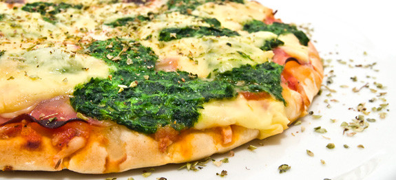 Close-up of a spinach and cheese pizza slice.