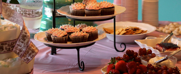 Cupcakes with frosting displayed on a two-tiered stand at a gathering.