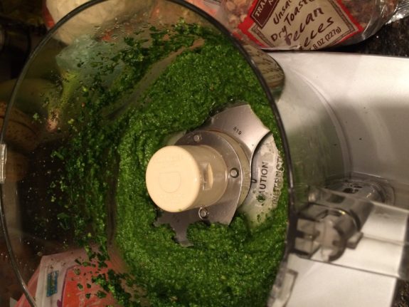 Blended green pesto sauce in a food processor bowl.