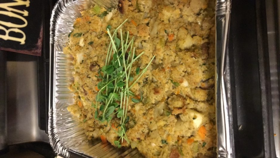 A baked savory stuffing garnished with fresh herbs in a tray.