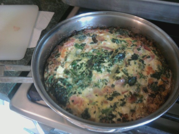 A creamy spinach and mushroom dish cooking in a pan.