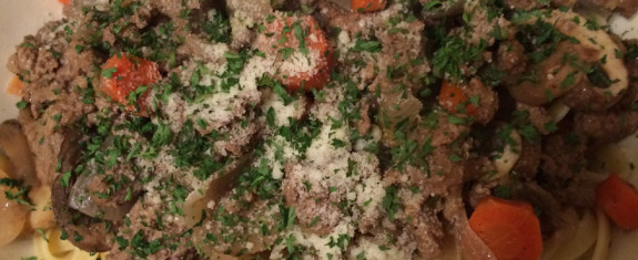 Close-up of meatballs topped with grated cheese and chopped parsley.