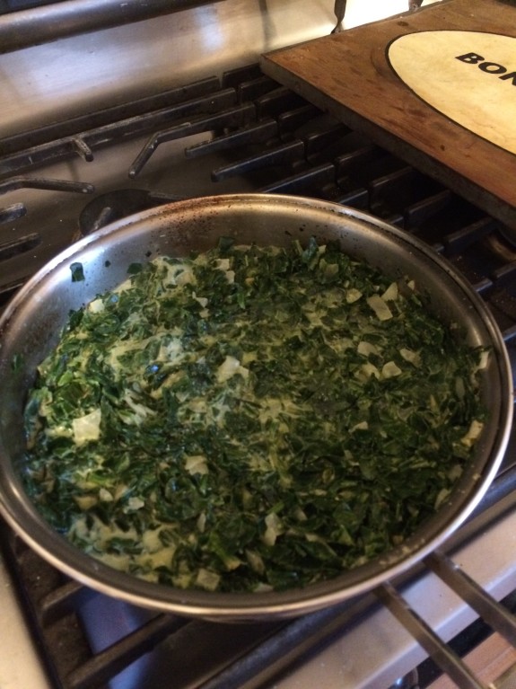 Sauteed chopped greens cooking in a stainless steel pan.