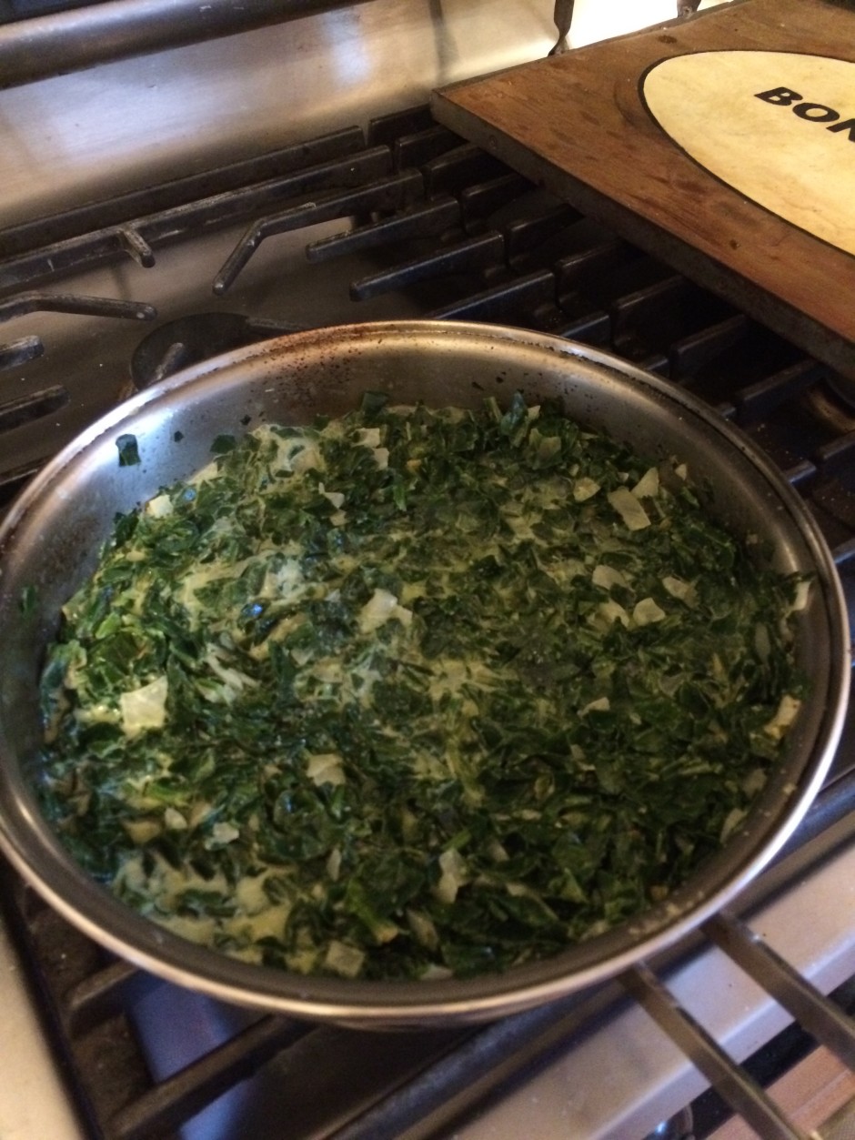 Sauteed chopped greens cooking in a stainless steel pan.