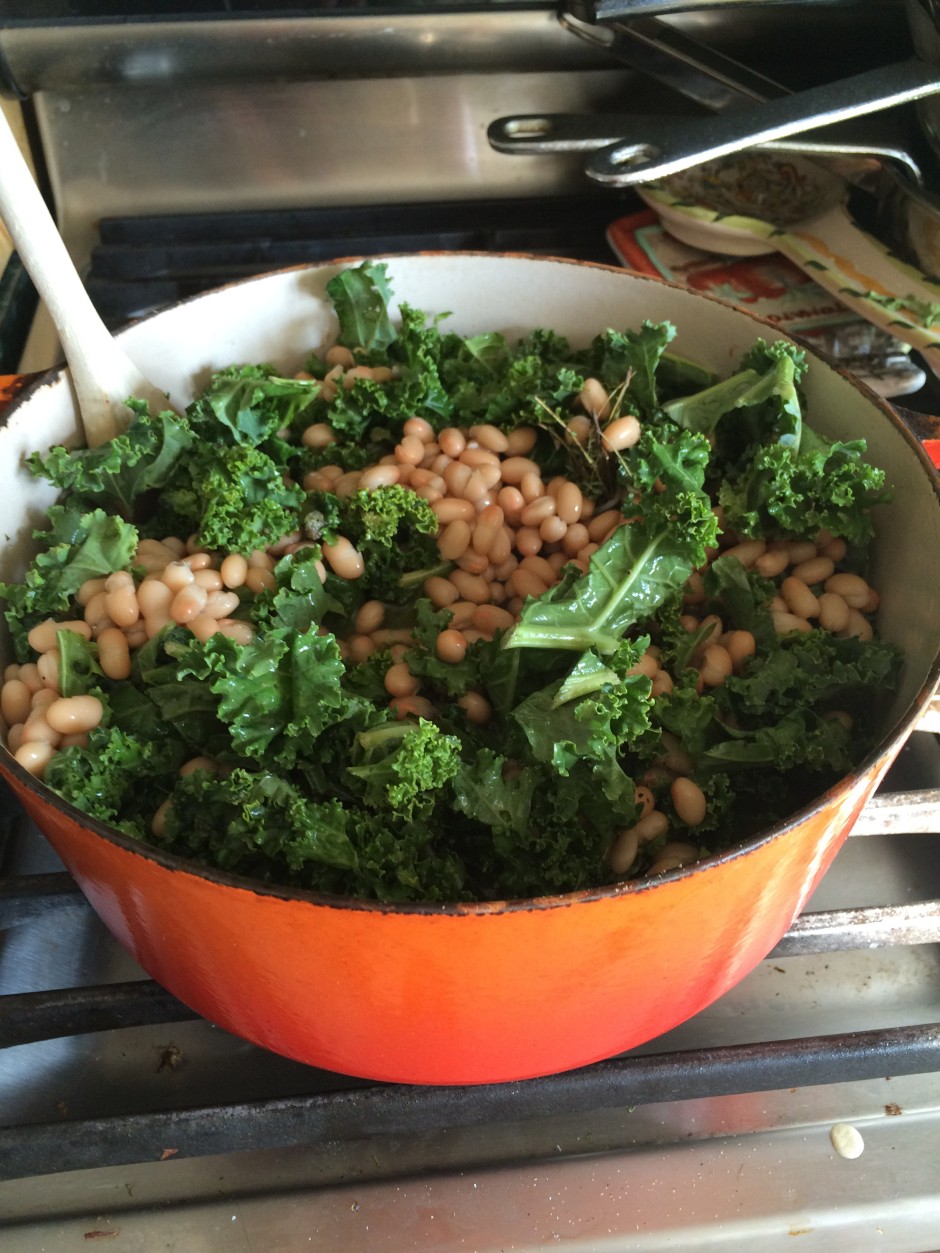 A pot of cooked lentils and kale on a stove.