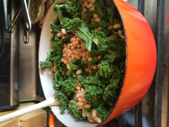 Orange bowl filled with cooked kale and chickpeas.