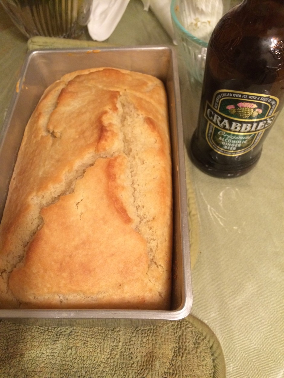 Freshly baked bread loaf next to a bottle of beer.