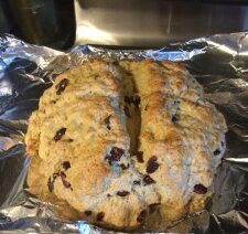 Baked scone with raisins on foil tray.