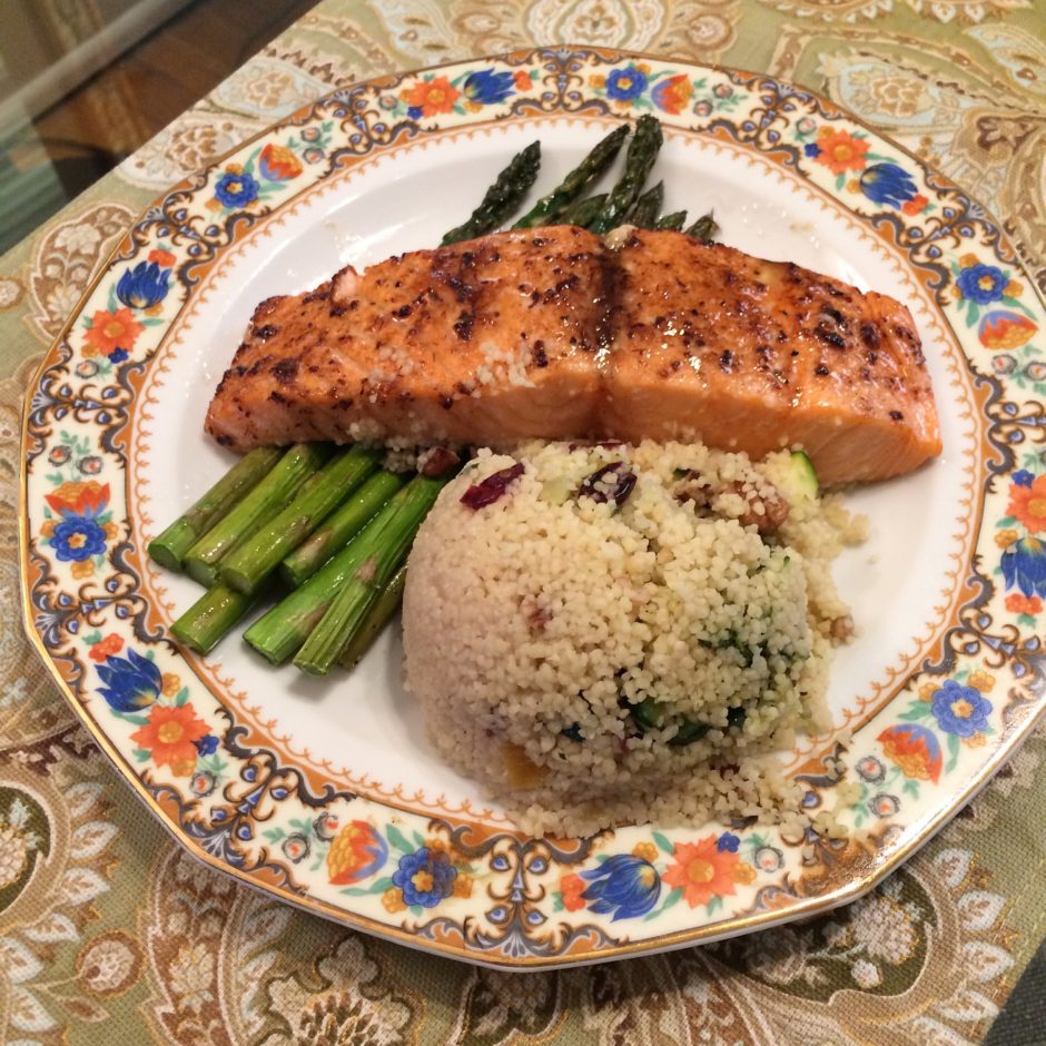 Grilled salmon served with asparagus and herb rice on a decorative plate.
