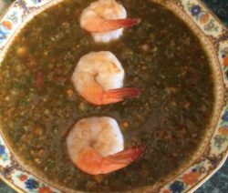 Shrimp on top of a dark soup.