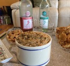 Dip, wine bottles, snacks on a table.