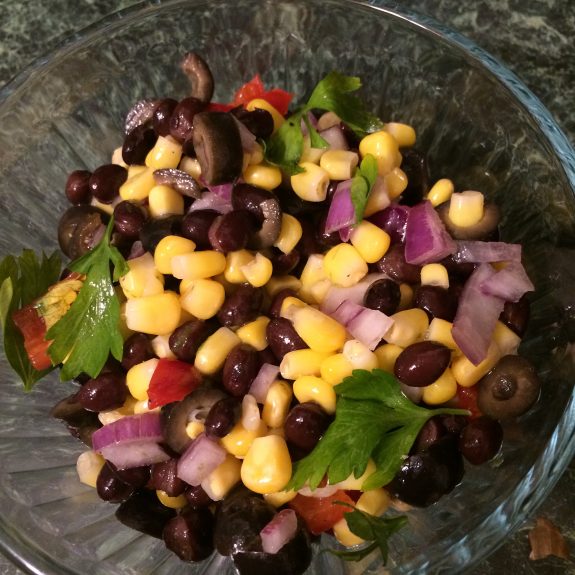 A colorful salad with chickpeas, black beans, corn, red onion, and greens.