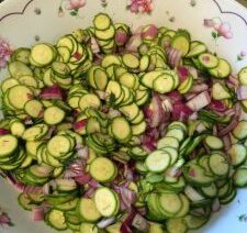 Sliced zucchini and onions in decorative bowl.