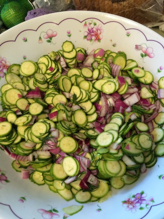 Bowl of thinly sliced cucumbers and red onions.