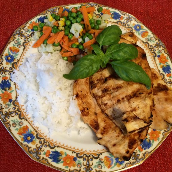 Grilled chicken breast served with white rice and mixed vegetables.