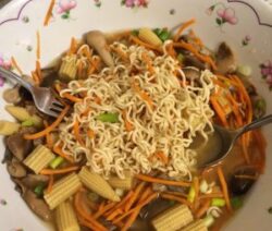 Noodles with vegetables in floral bowl.