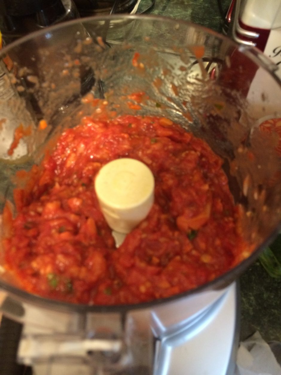 Fresh red salsa being blended in a food processor.