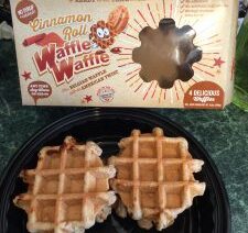 Cinnamon roll waffles on black plate.