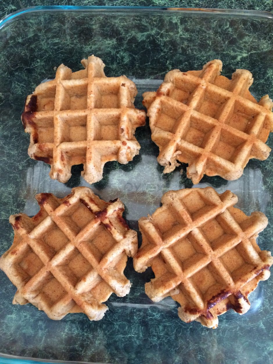 Four golden waffles on a blue surface.