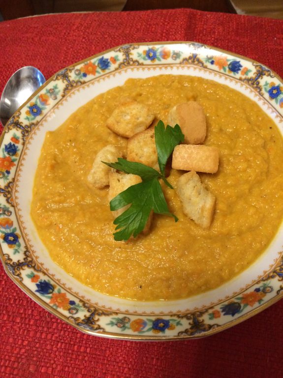 A bowl of creamy soup garnished with chicken and fresh parsley.