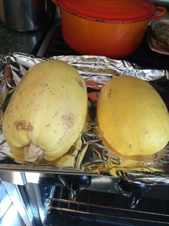 Two yellow spaghetti squashes resting on foil.