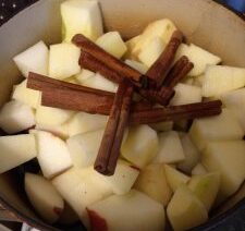 Chopped apples and cinnamon sticks in pot.