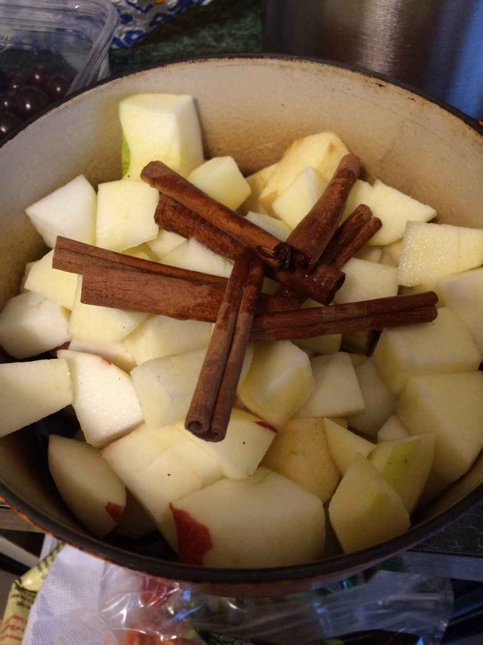 Chopped apples with cinnamon sticks in a bowl.