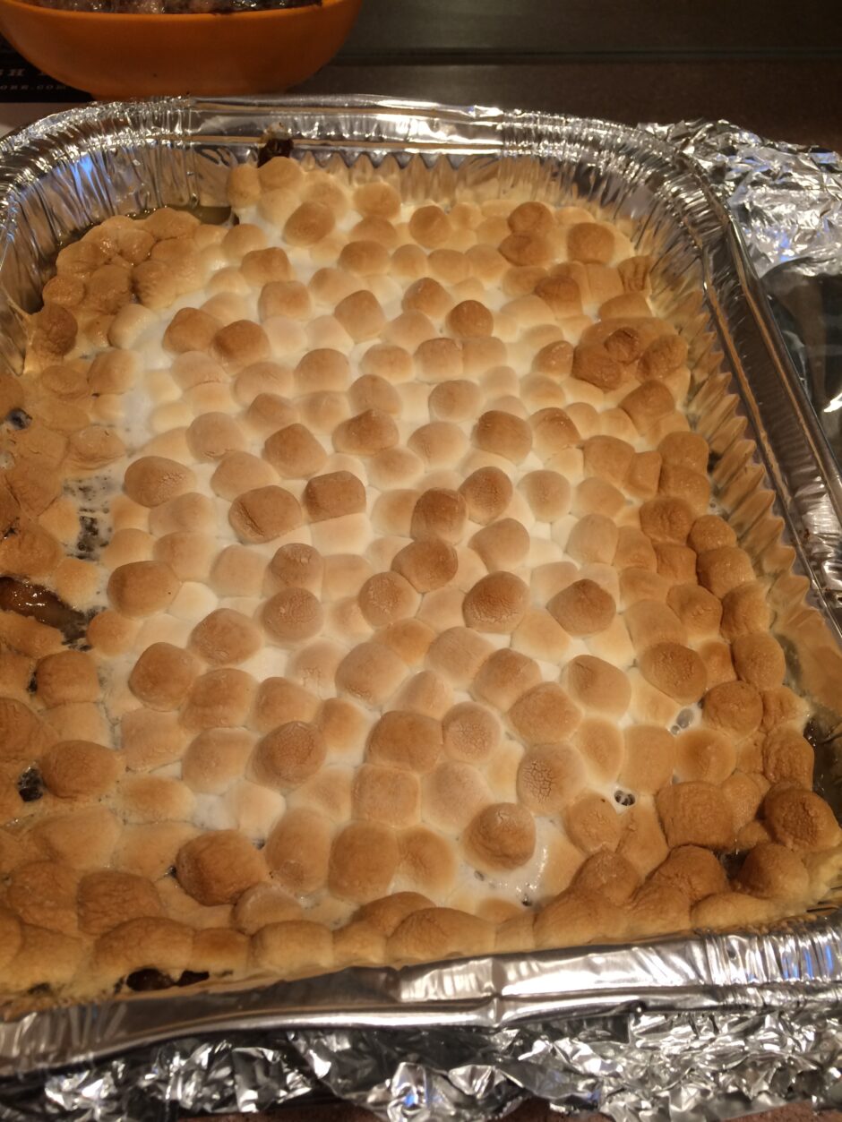 Baked dessert with toasted marshmallows on top in a foil tray.