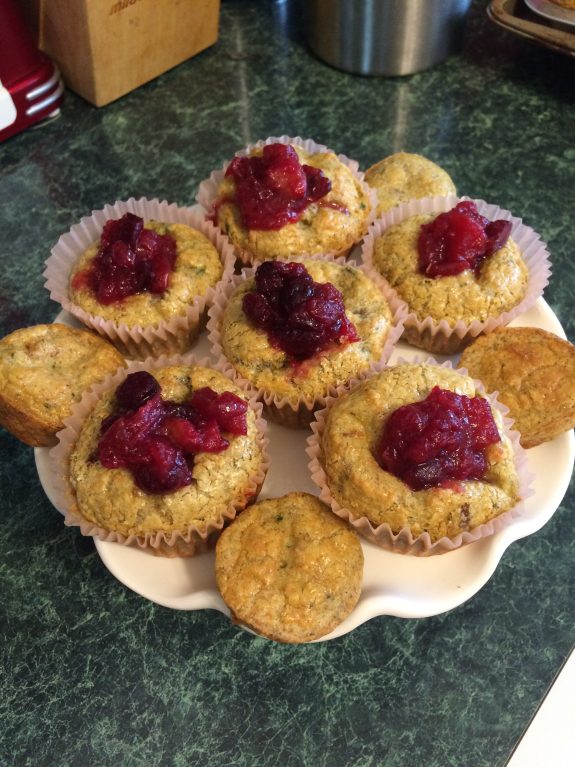 Plate of muffins topped with berry jam on a green table.