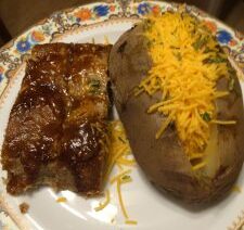 Barbecue ribs and baked potato with cheese.