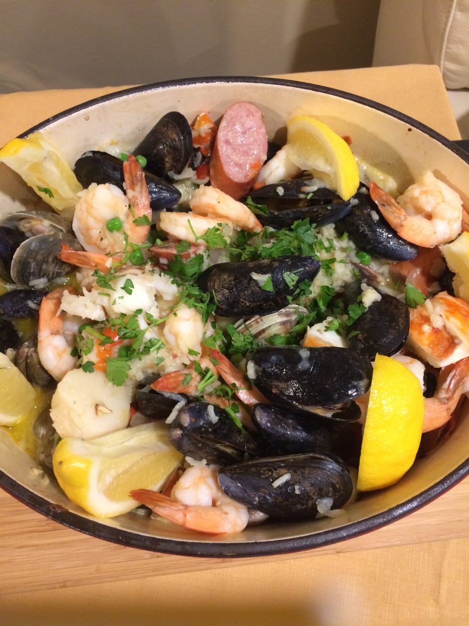 A vibrant seafood dish with shrimp, mussels, and lemon wedges.