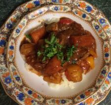 Beef stew with vegetables on decorative plate.