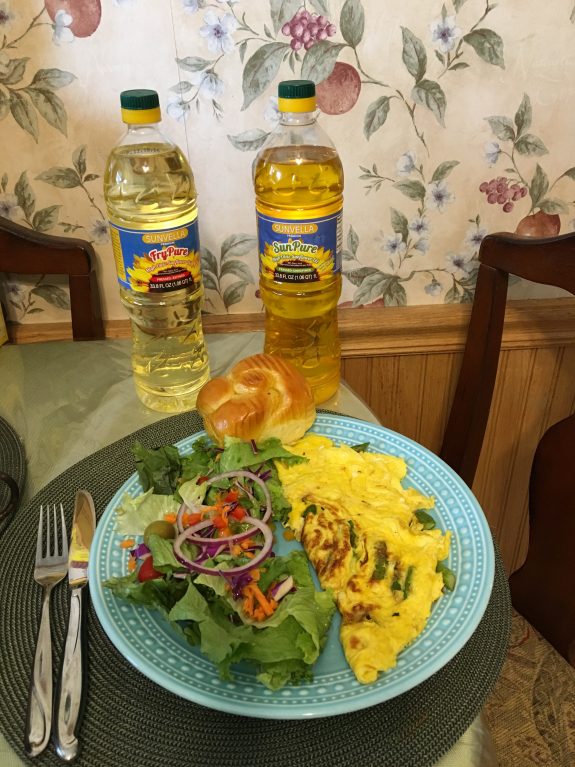A colorful plate with scrambled eggs, salad, and a roll, plus two bottles of vegetable oil.