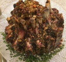 Cooked crown roast with herbs on platter.
