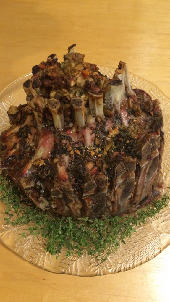 A large cooked piece of meat with herbs and sauce on a plate.