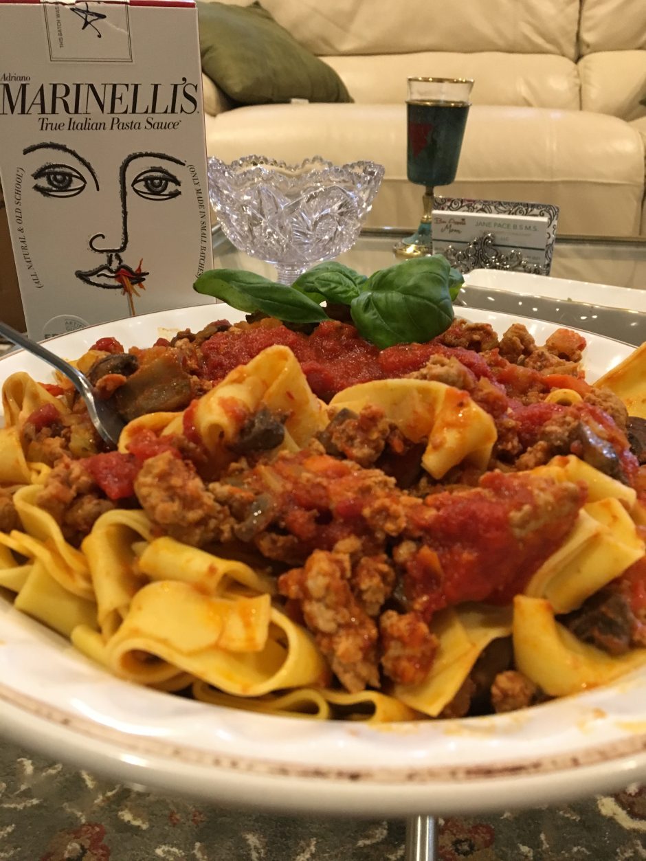 Plate of tortellini pasta with rich meat sauce and broccoli on the side.