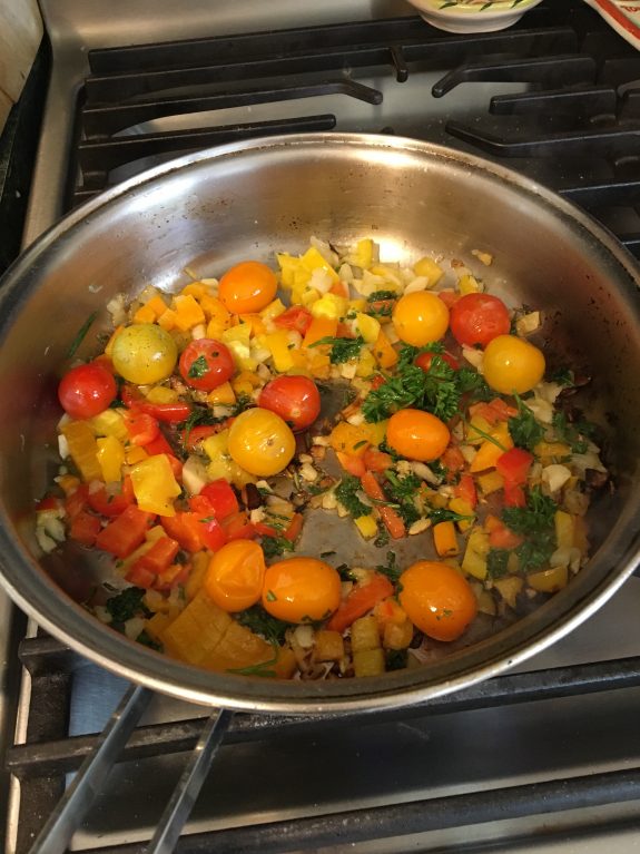 A colorful vegetable sauté with tomatoes and greens in a pan.