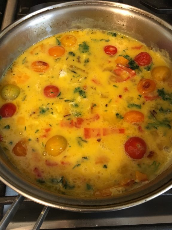 A colorful vegetable omelette cooking in a pan.