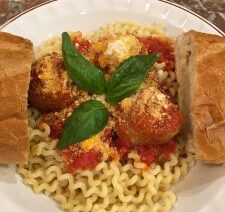 Pasta with meatballs, bread, and basil garnish.