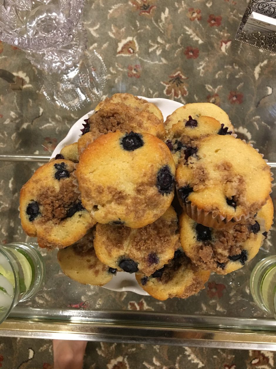 A pile of blueberry muffins in a plastic container.