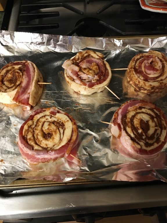 Bacon-wrapped cinnamon rolls on a baking tray.