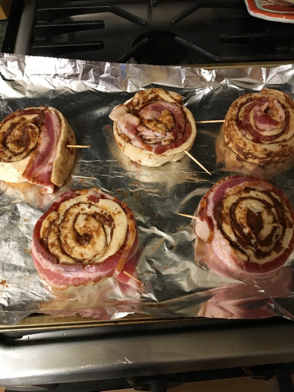 Bacon-wrapped cinnamon rolls on a baking tray.