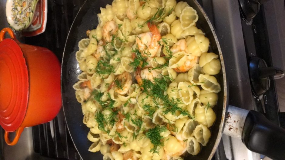 Shrimp pasta with herbs in a black skillet.